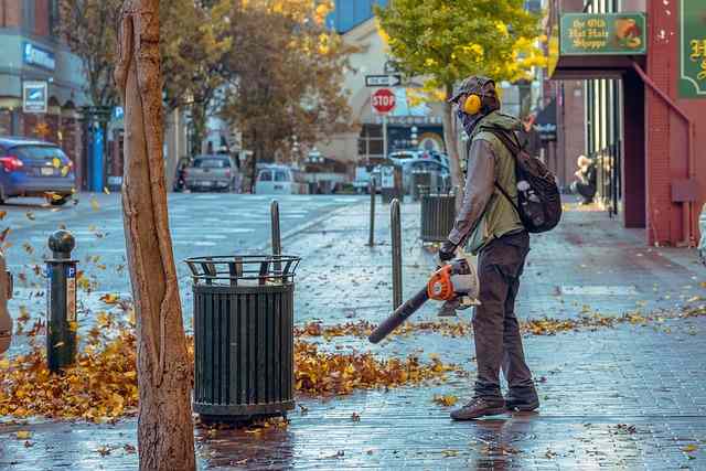 Un trabajdor usando la sopladora de hojas en la calle
